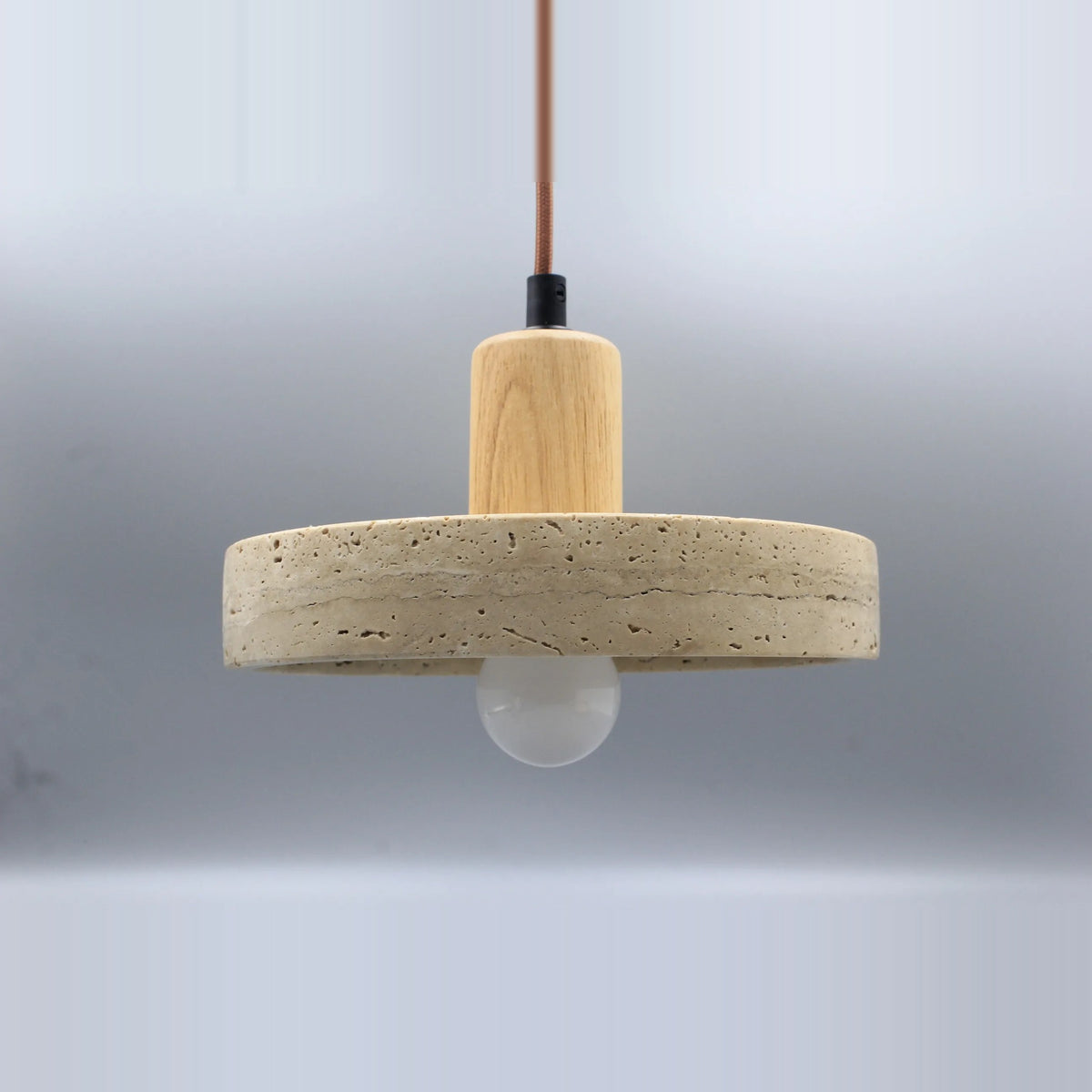 Stone disc pendant light with a light wood-tone top and the included bulb