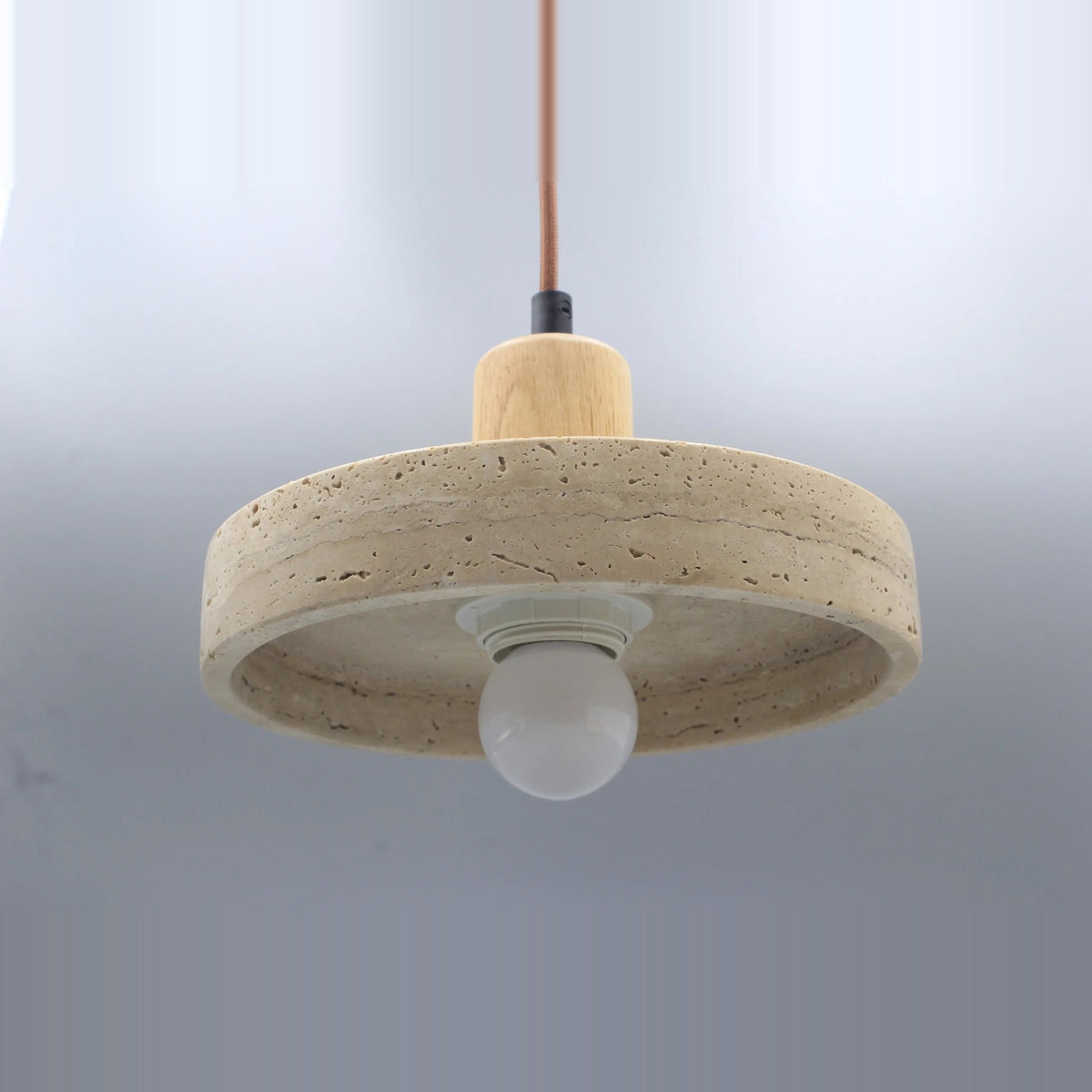 Stone disc pendant light with a light wood-tone top, seen from below