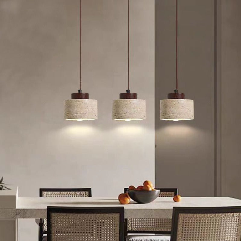 Three 10 cm travertine stone pendants over a dining table